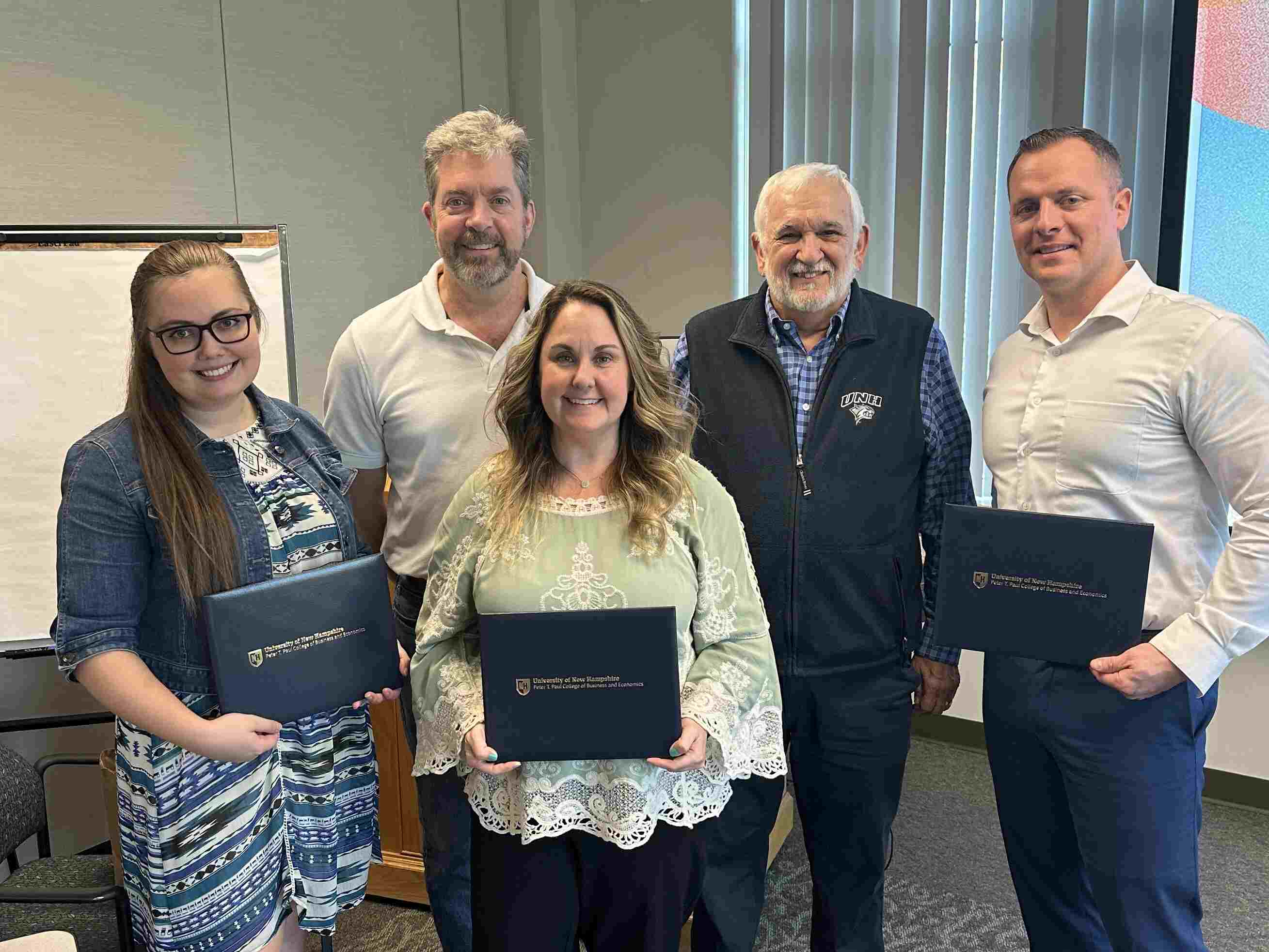 A photo of five AGNE employees, three of them holding awards in front of them.